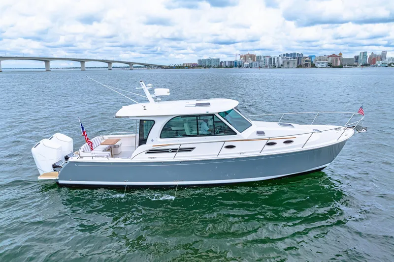  Yacht Photos Pics 2024 Back Cove 39O boat on water with cityscape and bridge in background.