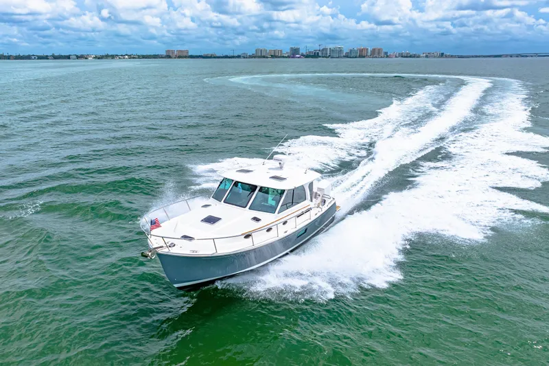  Yacht Photos Pics 2024 Back Cove 39O cruising on open water with city skyline in background.