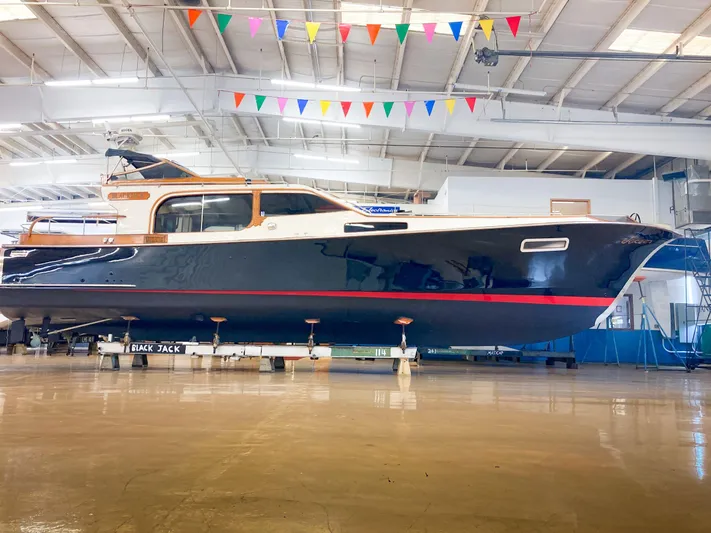 Blackjack Yacht Photos Pics 1984 Midnight Lace Rumrunner yacht in a spacious indoor facility with colorful flags above.