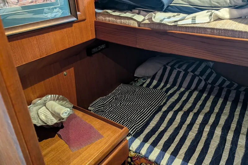 Moments Notice Yacht Photos Pics Cozy cabin interior of 1981 Sea Ranger 47 with striped bedding and wooden furnishings.