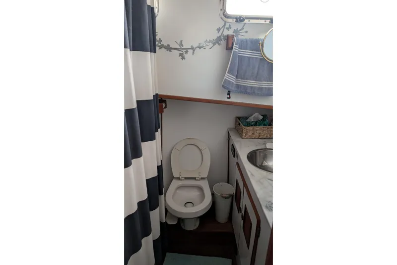 Moments Notice Yacht Photos Pics 1981 Sea Ranger 47 bathroom with toilet, sink, and striped shower curtain.
