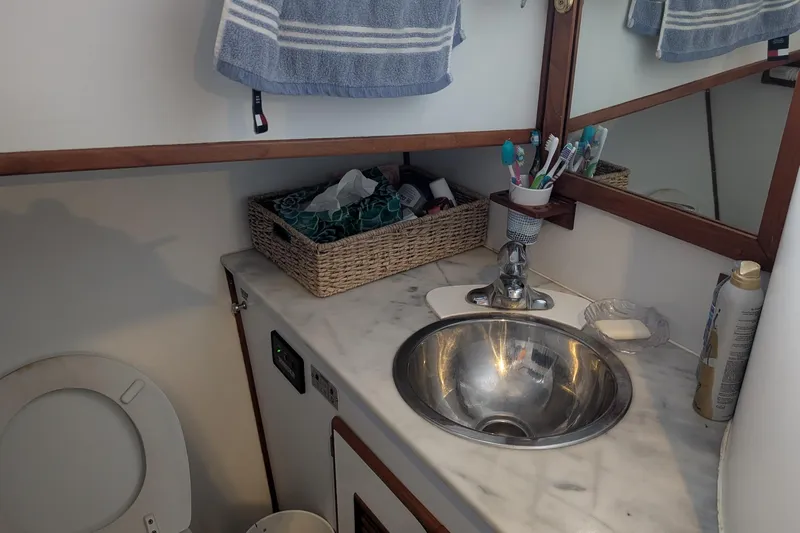 Moments Notice Yacht Photos Pics Bathroom interior of 1981 Sea Ranger 47 yacht with sink, mirror, and toiletries.