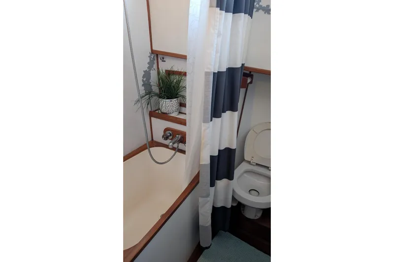 Moments Notice Yacht Photos Pics 1981 Sea Ranger 47 yacht bathroom with shower, toilet, and striped curtain.
