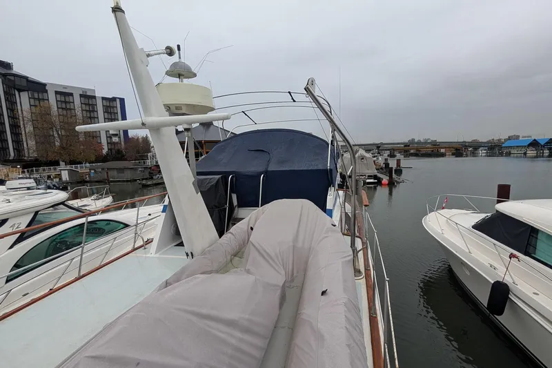 Moments Notice Yacht Photos Pics 1981 Sea Ranger 47 yacht docked at marina, surrounded by other boats on a cloudy day.