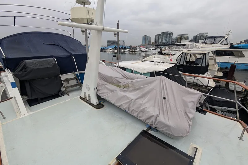 Moments Notice Yacht Photos Pics 1981 Sea Ranger 47 yacht docked at marina, covered equipment on deck, cityscape background.