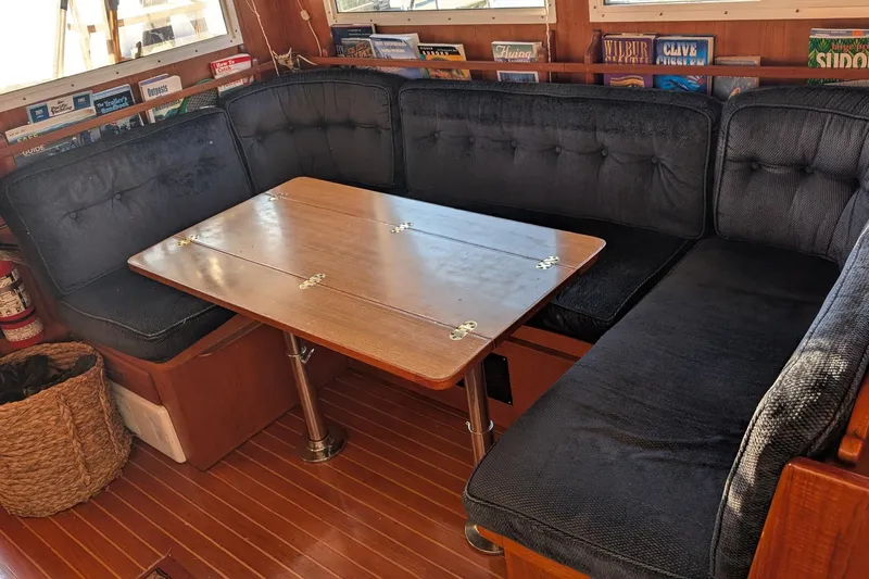 Moments Notice Yacht Photos Pics Cozy dining area in 1981 Sea Ranger 47 yacht with wooden table and cushioned seating.