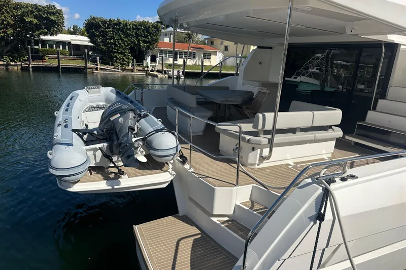 Euphoria Yacht Photos Pics 2024 Leopard 53 Powercat yacht with tender boat on deck, docked by waterfront homes.