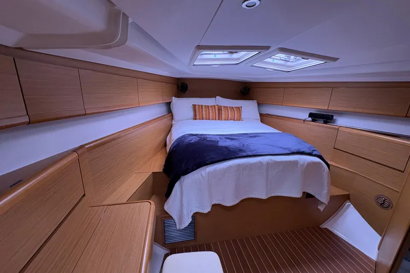Star IV Yacht Photos Pics Luxurious cabin interior of 2010 Jeanneau 50DS sailboat with cozy bed and wooden finish.