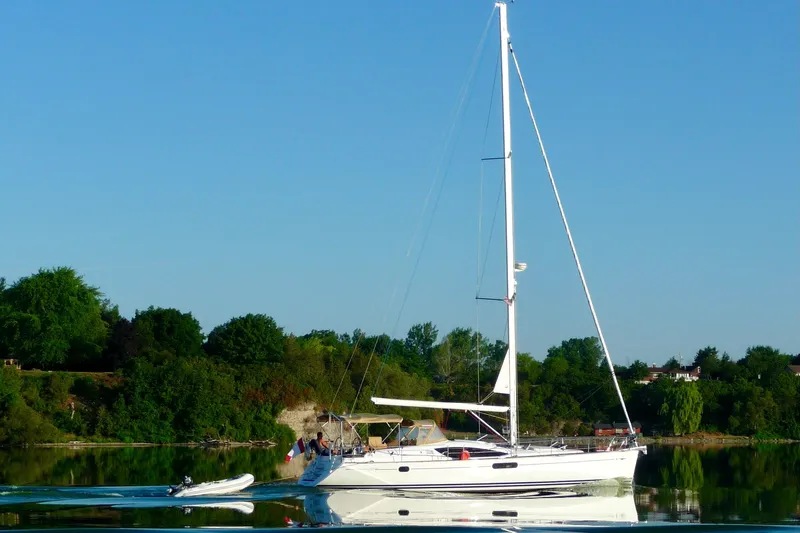 Star IV Yacht Photos Pics 2011 Jeanneau Sun Odyssey 50 DS sailing on calm waters, surrounded by lush greenery.