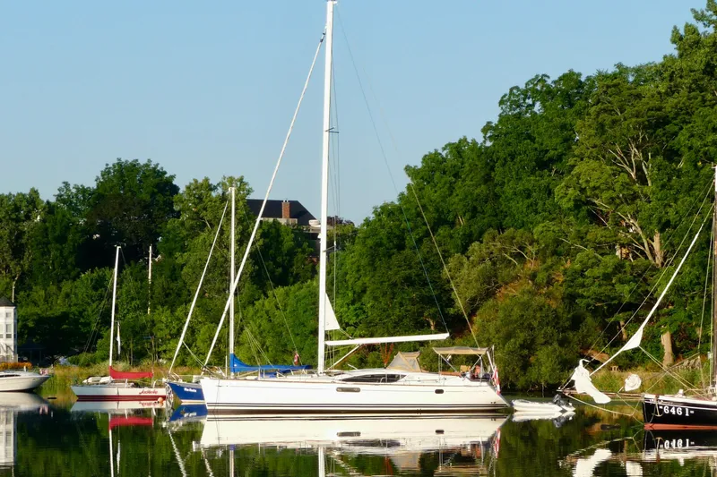 Star IV Yacht Photos Pics 2011 Jeanneau Sun Odyssey 50 DS sailboat docked by lush green trees.