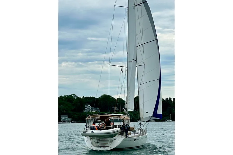 Star IV Yacht Photos Pics Sailing yacht Jeanneau Sun Odyssey 50 DS, 2011, on calm waters with lush shoreline.