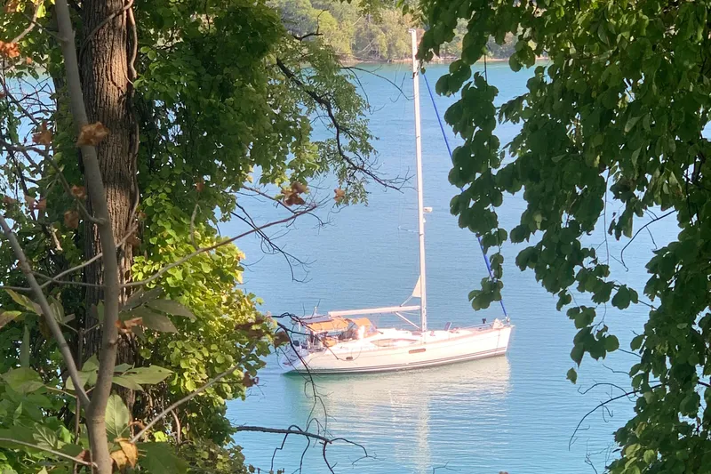 Star IV Yacht Photos Pics Sailboat Jeanneau Sun Odyssey 50 DS, 2011, anchored on serene blue water, framed by lush greenery.