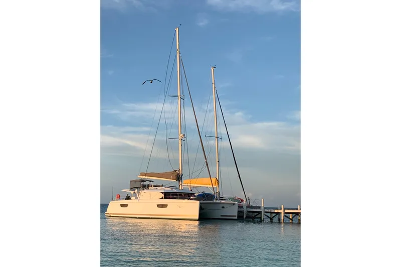 Nowhere Yacht Photos Pics 2016 Fountaine Pajot SABA 50 catamaran docked at sunset with clear skies.