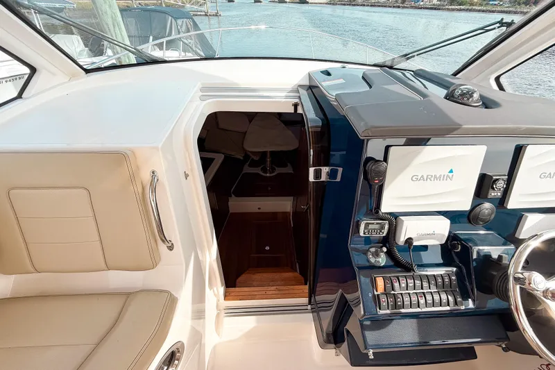  Yacht Photos Pics 2016 Pursuit OS 355 Offshore helm with Garmin navigation, beige seating, and cabin entrance.