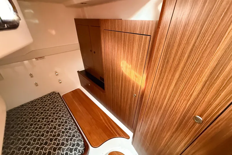  Yacht Photos Pics 2016 Pursuit OS 355 Offshore cabin interior with wood paneling and patterned bedding.