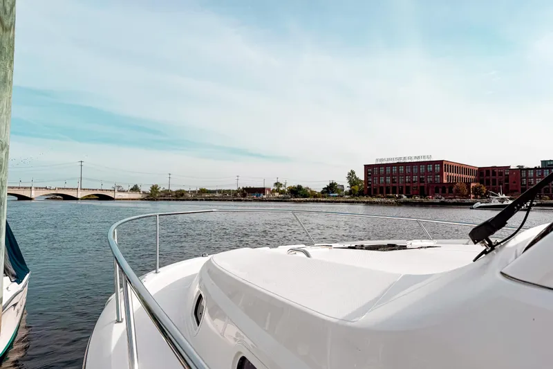  Yacht Photos Pics 2016 Pursuit OS 355 Offshore boat on calm water near a bridge and red brick building.