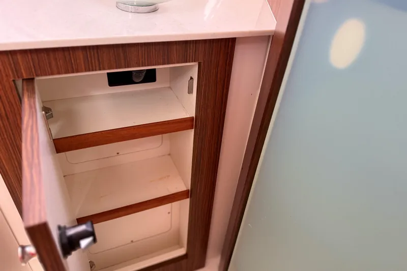  Yacht Photos Pics Open wooden cabinet with shelves inside a 2016 Pursuit OS 355 Offshore boat.