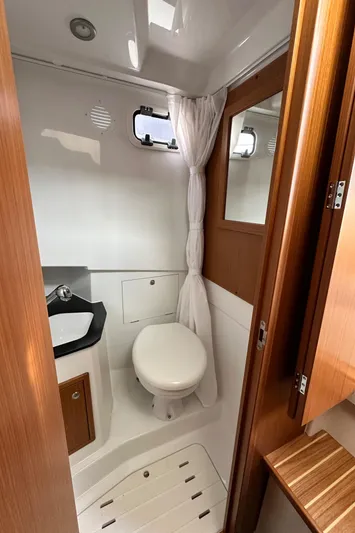  Yacht Photos Pics 2023 Sargo 28 boat bathroom with toilet, sink, and wooden accents.