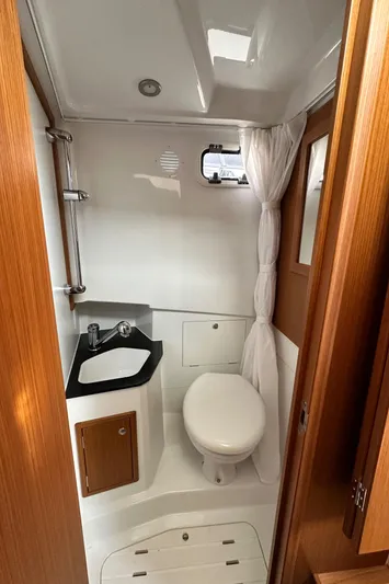  Yacht Photos Pics 2023 Sargo 28 boat bathroom with sink, toilet, and wooden accents.