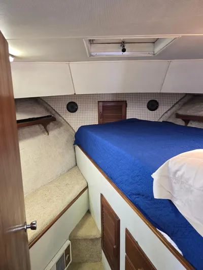 Aurora Yacht Photos Pics 1982 Tollycraft 37 Sportfish Convertible cabin with blue bedding and wooden accents.