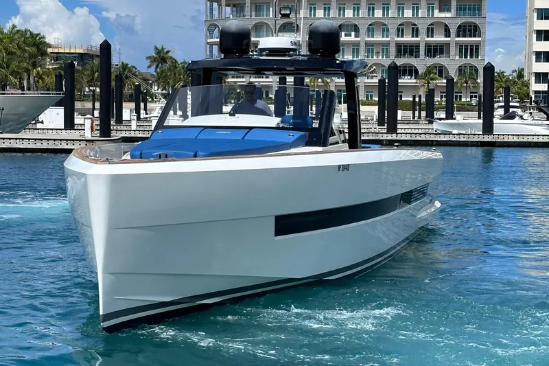 Uni Yacht Photos Pics 2020 Fjord 44 Open yacht cruising in a marina with modern buildings in the background.