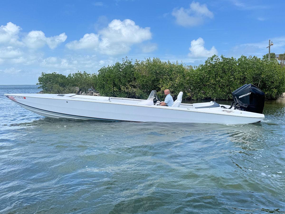 2022 Phantom 32 CC boat on water, surrounded by lush greenery and blue sky.