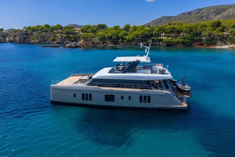 Vahewa Yacht Photos Pics 2024 Sunreef Power Cat yacht in serene blue waters near a lush coastline.