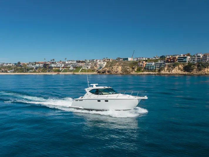 Niksen Yacht Photos Pics 2013 Tiara Yachts 3500 Sovran cruising on clear blue water near coastal homes.