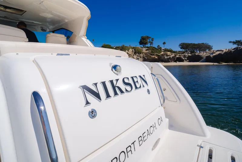 Niksen Yacht Photos Pics 2013 Tiara Yachts 3500 Sovran, "NIKSEN," docked near a scenic beach.