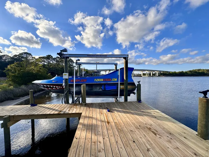 Scream Machine Yacht Photos Pics 2016 Smoky Mountain 25 Passenger Jet Boat docked by a scenic river under a blue sky.