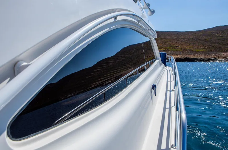  Yacht Photos Pics Bertram 570 yacht (2006) reflecting ocean and coastline under clear blue sky.