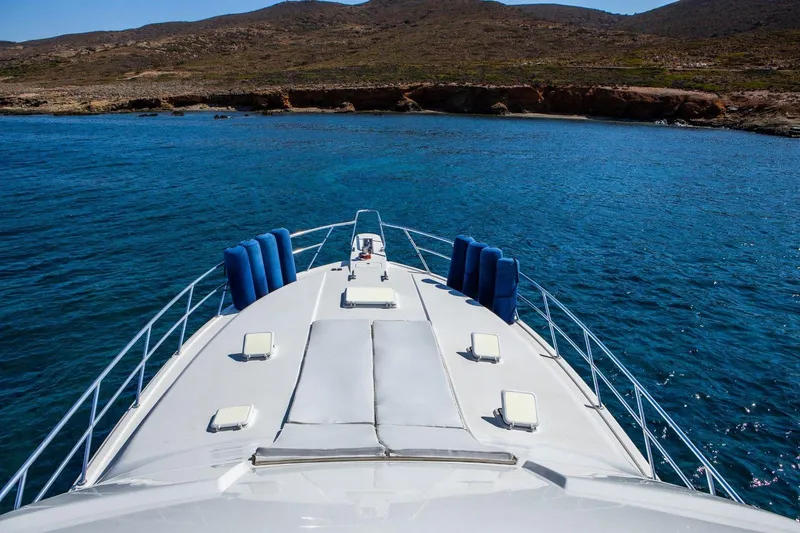  Yacht Photos Pics 2006 Bertram 570 yacht cruising in clear blue waters near a rocky coastline.