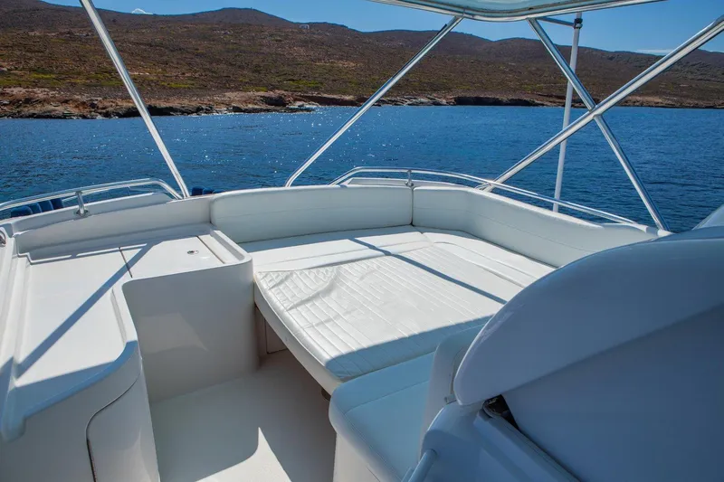  Yacht Photos Pics 2006 Bertram 570 yacht deck with white seating, overlooking serene blue waters and distant hills.