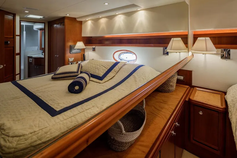  Yacht Photos Pics Luxurious cabin interior of a 2006 Bertram 570 yacht with elegant bedding and wooden accents.