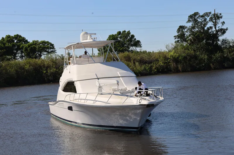  Yacht Photos Pics 2012 Bertram 511 yacht cruising on a calm river with lush greenery.