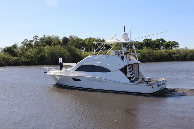  Yacht Photos Pics 2012 Bertram 511 yacht cruising on a calm river with lush greenery.