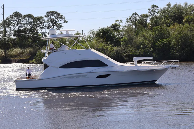  Yacht Photos Pics 2012 Bertram 511 yacht cruising on a calm river with lush greenery in the background.
