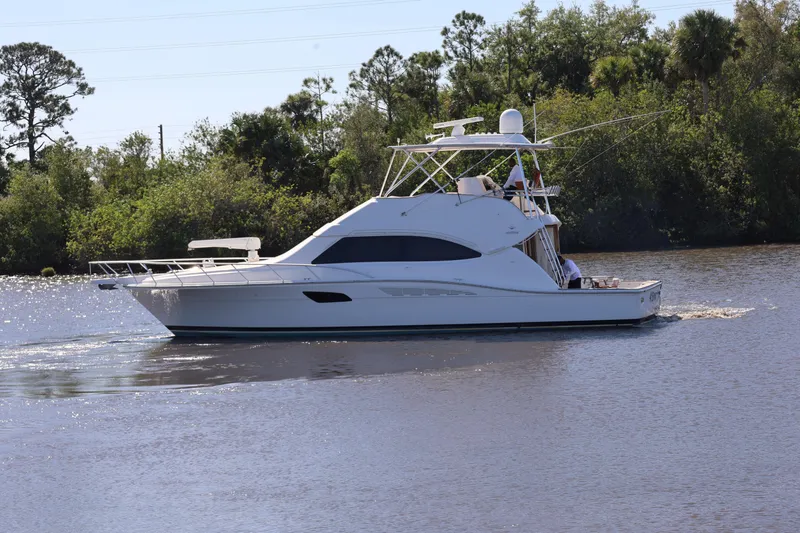  Yacht Photos Pics 2012 Bertram 511 yacht cruising on a calm river with lush greenery in the background.