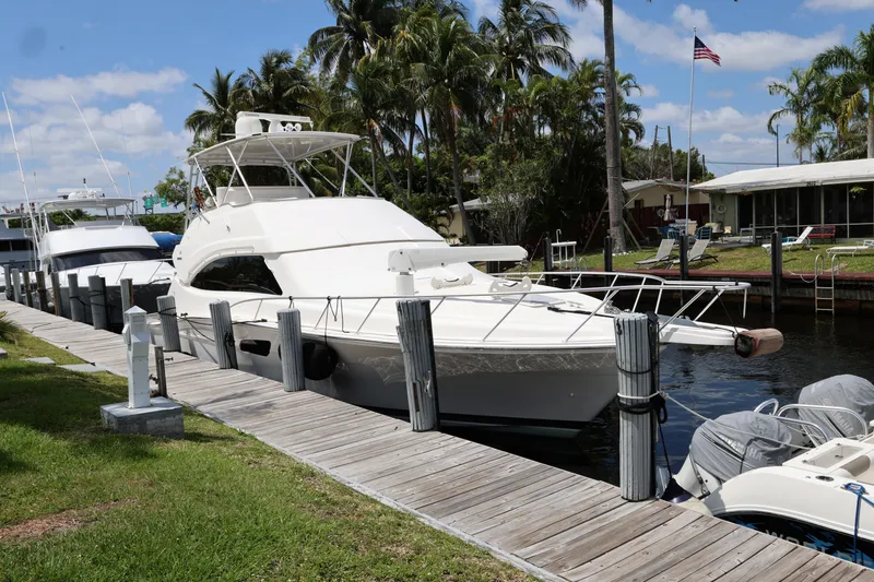  Yacht Photos Pics 2012 Bertram 511 yacht docked by a wooden pier, surrounded by palm trees and clear skies.