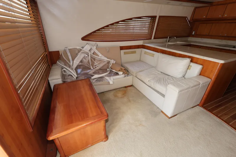  Yacht Photos Pics Interior of 2012 Bertram 511 yacht with white seating, wooden table, and blinds.