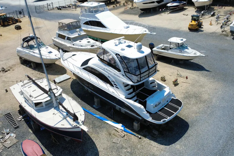  Yacht Photos Pics 2007 Sea Ray 52 Sedan Bridge yacht in a boatyard, surrounded by various vessels.
