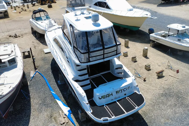  Yacht Photos Pics 2007 Sea Ray 52 Sedan Bridge yacht in a boatyard, surrounded by other vessels.
