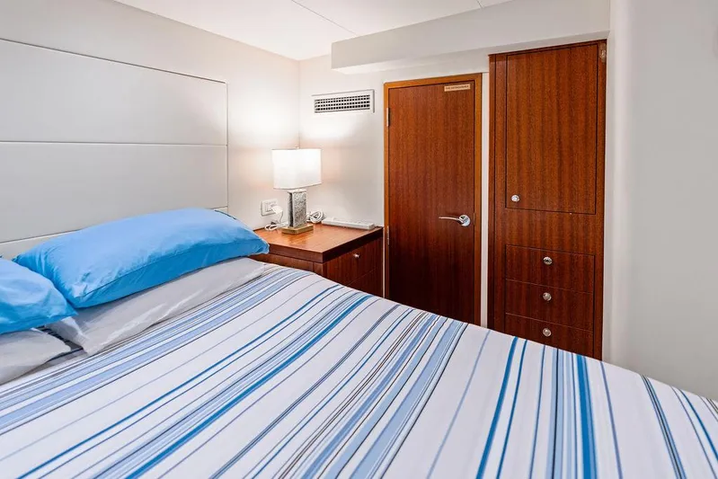 Griffin Yacht Photos Pics Interior of 2013 Hatteras 80 Motor Yacht bedroom with striped bedding and wooden cabinetry.