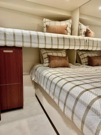 Griffin Yacht Photos Pics Interior of 2013 Hatteras 80 Motor Yacht with striped bedding and wooden cabinet.