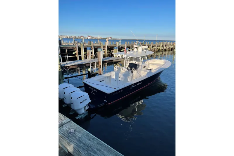Flag Blue Yacht Photos Pics 2018 Regulator 34SS boat docked with triple Yamaha engines, clear blue sky.