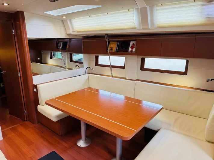 Flight Risk Yacht Photos Pics Interior of 2020 Beneteau Oceanis 51.1 yacht with wooden dining table and cream seating.