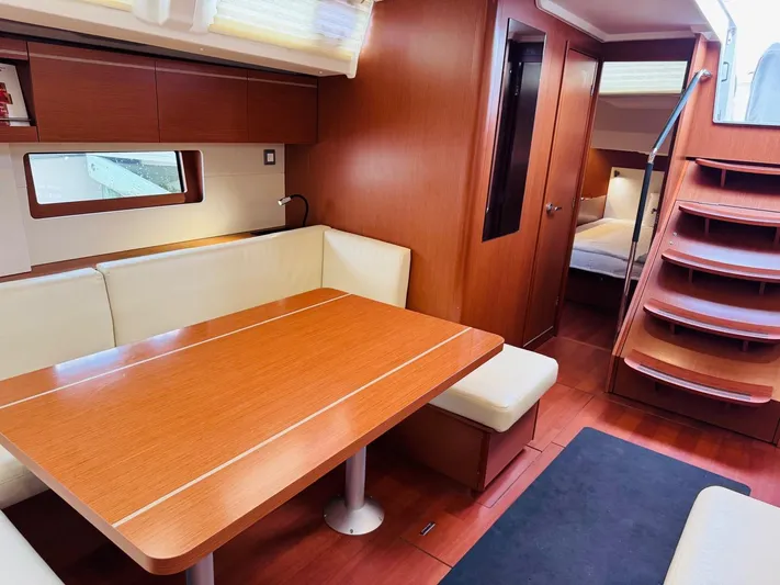 Flight Risk Yacht Photos Pics Luxurious interior of 2020 Beneteau Oceanis 51.1 yacht with wooden dining area and staircase.