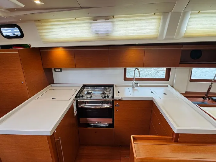 Flight Risk Yacht Photos Pics Modern kitchen interior of 2020 Beneteau Oceanis 51.1 yacht with wood cabinetry and stainless steel appliances.