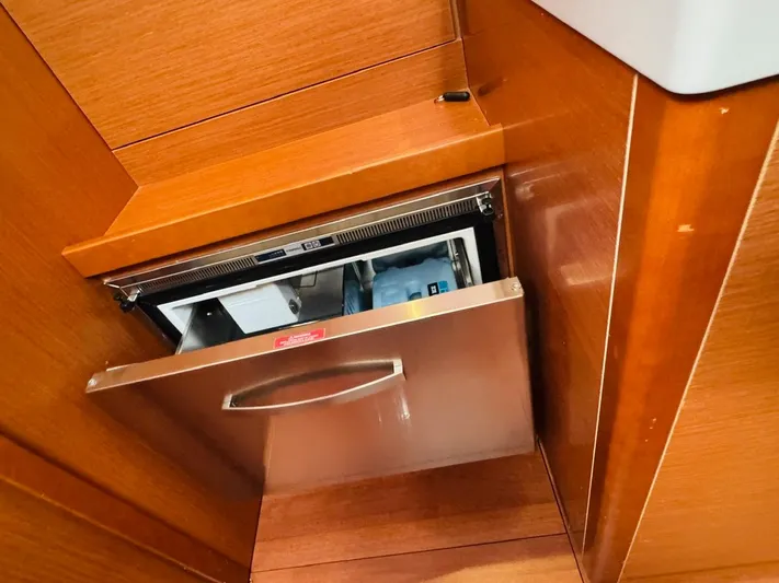 Flight Risk Yacht Photos Pics Built-in drawer refrigerator on 2020 Beneteau Oceanis 51.1 yacht, featuring sleek wood paneling.