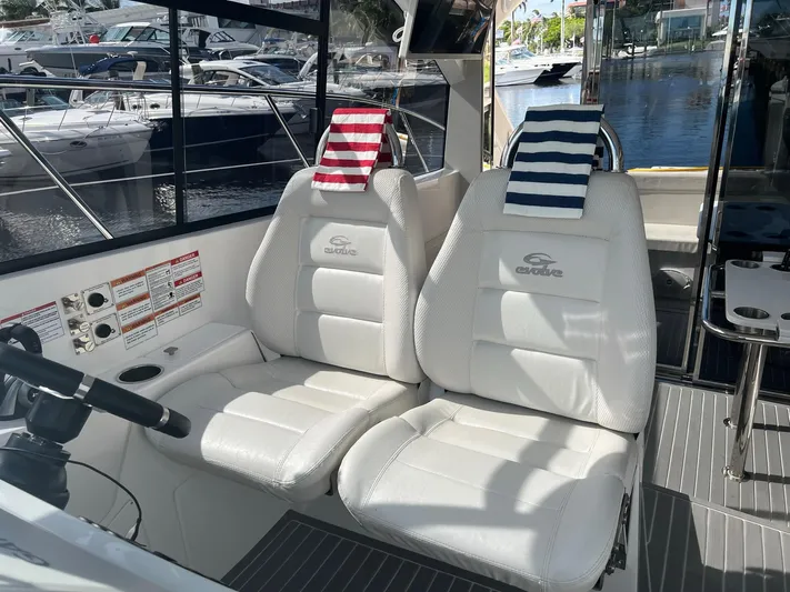 Romaniac Yacht Photos Pics 2021 Evolve 400HT boat interior with white captain seats and striped towels, docked at marina.